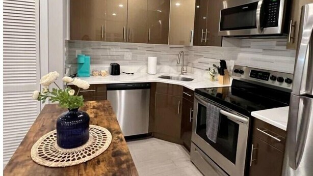 A modern kitchen with stainless steel appliances, a dishwasher, and wooden cabinets. - 304 Stunning and comfy  1BDR APT in Center city (Philadelphia)