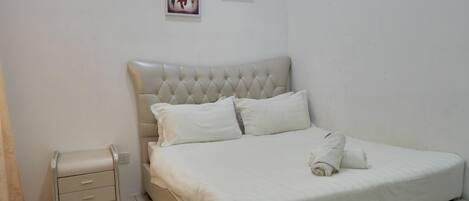 Un dormitorio con una cama grande, dos mesitas de noche y dos cuadros en la pared.
