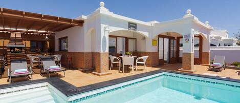 A poolside area with lounge chairs, a bar, and a covered seating area.