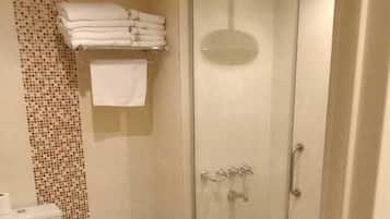Et badeværelse med toilet, bidet og brusekabine i glas.