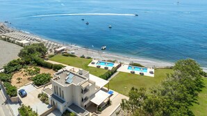 Una propiedad costera con piscina, playa y barcos en el agua.