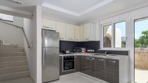 Una cocina moderna con electrodomésticos de acero inoxidable, armarios grises y un amplio ventanal con vistas al exterior.