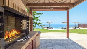 Una zona de barbacoa con chimenea de piedra, mobiliario exterior y vistas al océano.