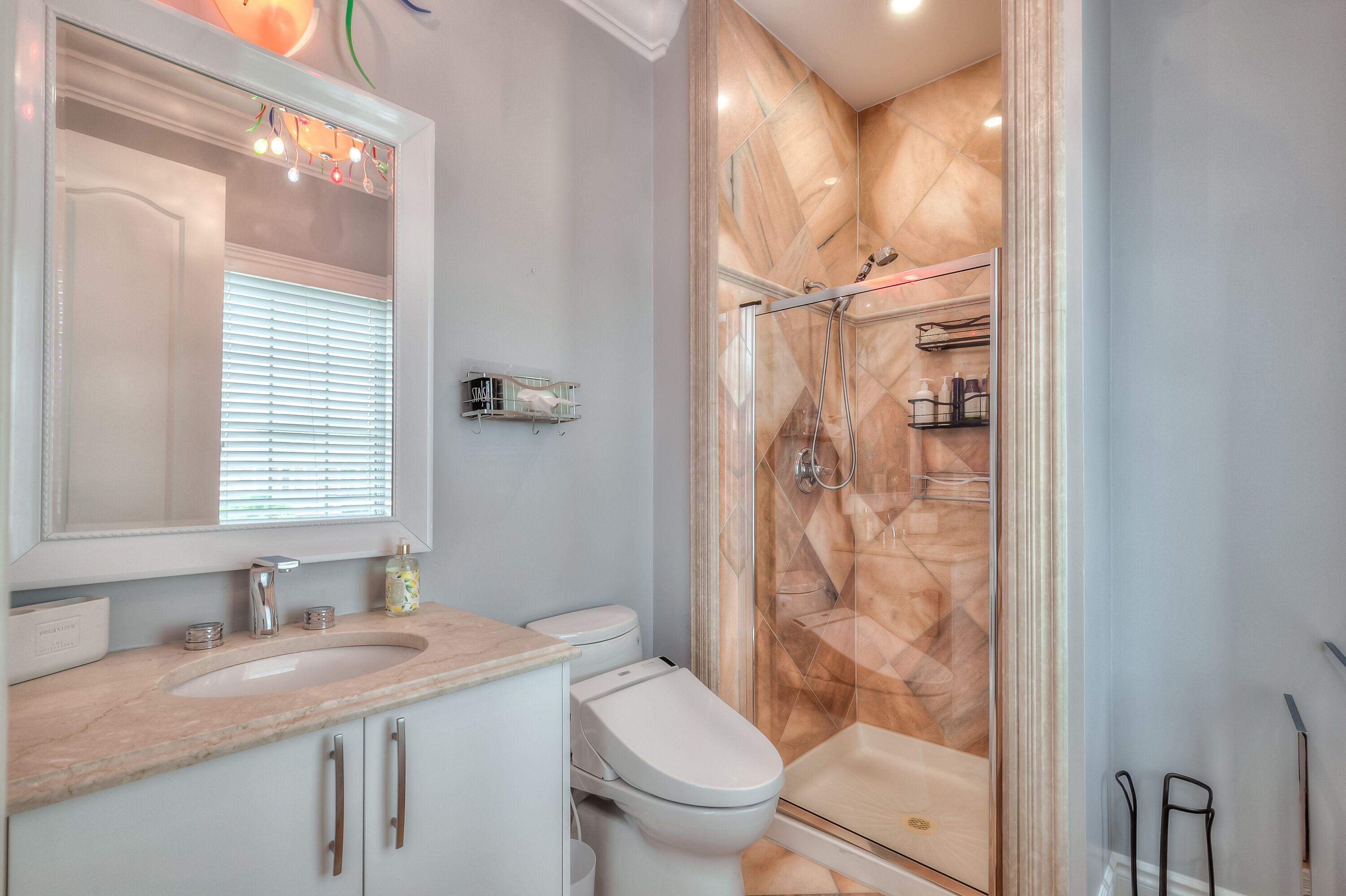 Un bagno moderno con un lavandino in marmo, un water e una cabina doccia in vetro.