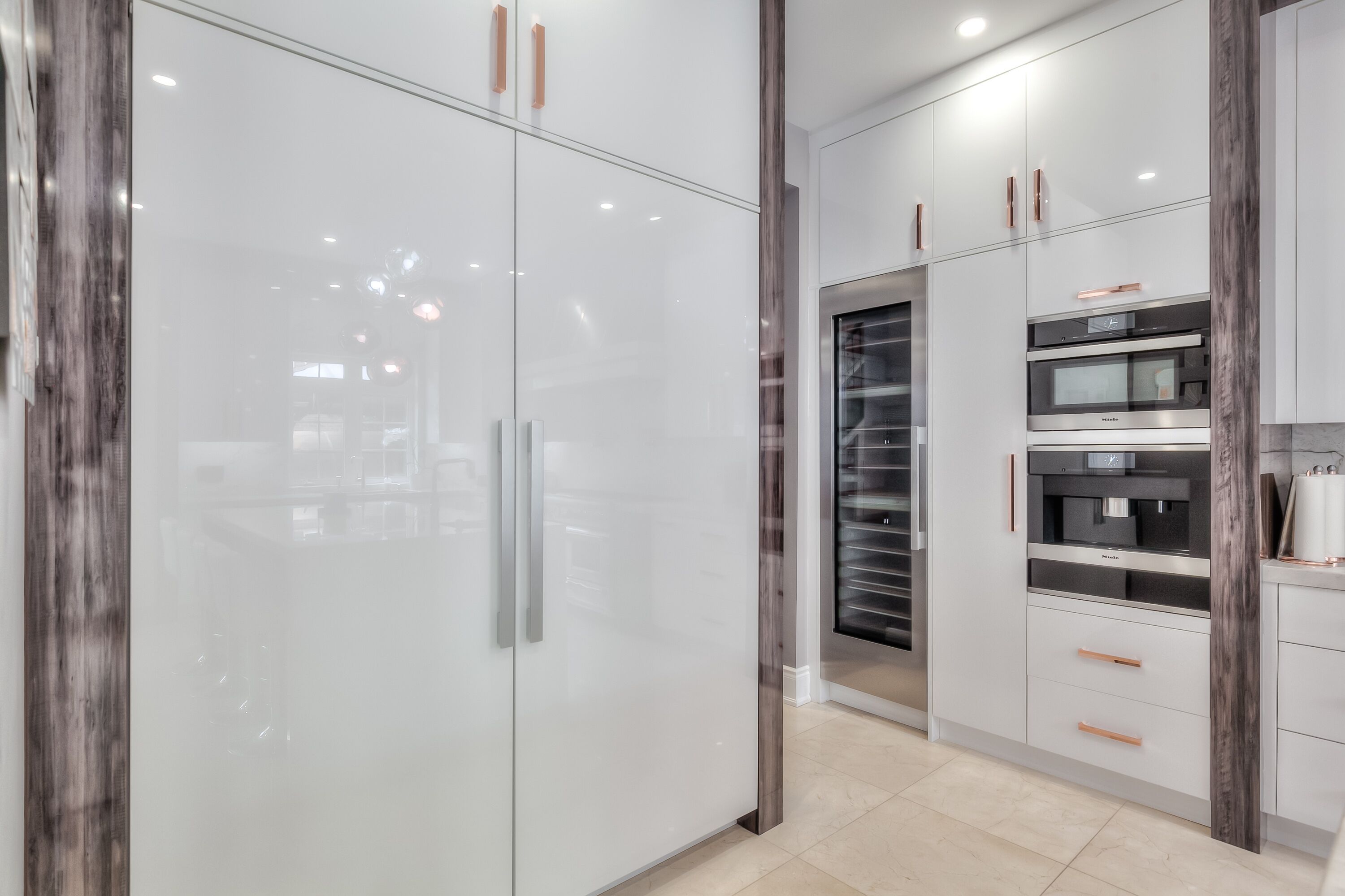 A modern kitchen with white cabinets, a built-in oven, and a coffee machine.