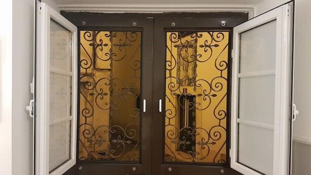 Une paire de portes à double battant, agrémentées de motifs métalliques complexes et de panneaux de verre.