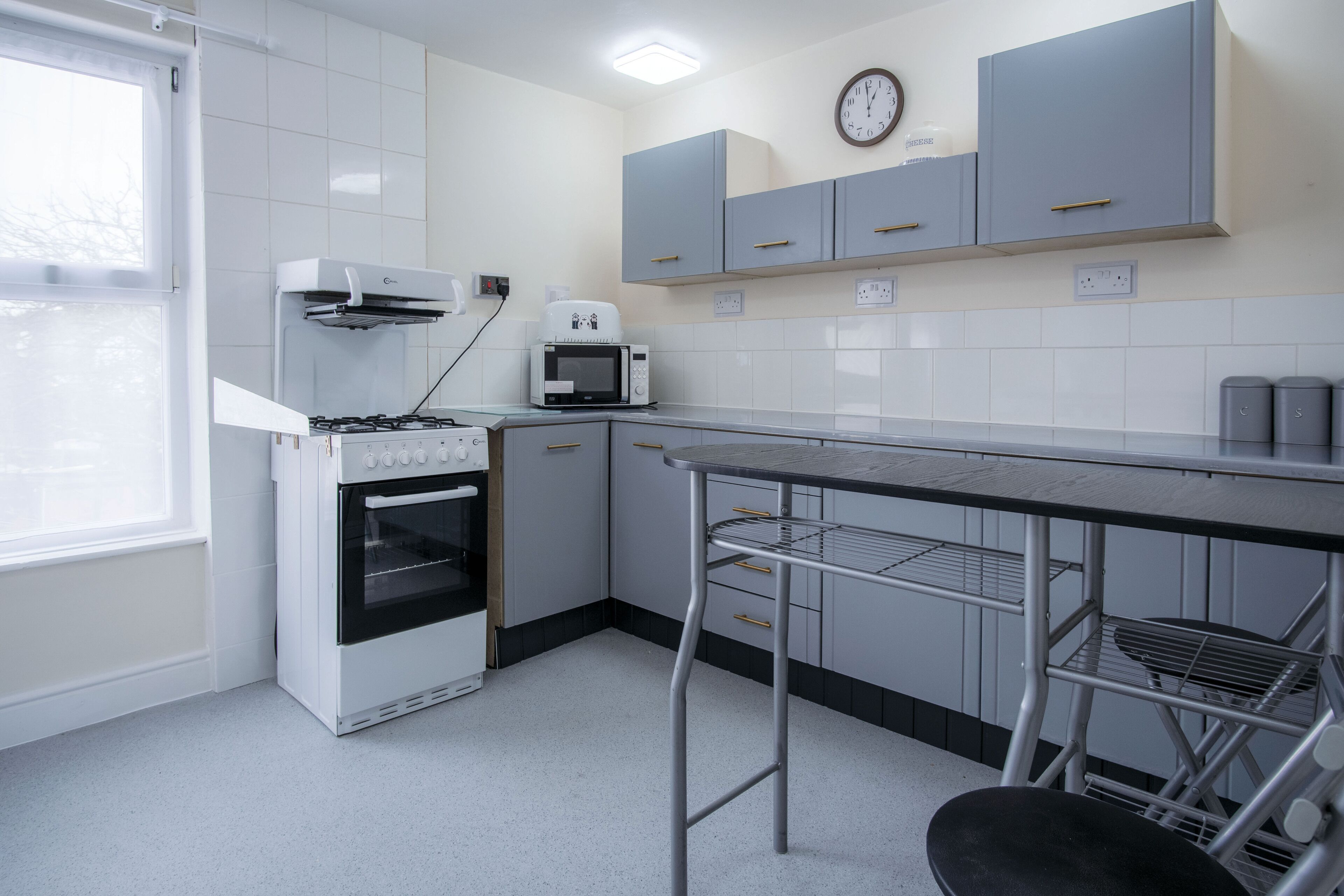 A kitchen with white cabinets, a microwave, a stove, and a metal bar counter.