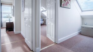 A room with white walls, a skylight, and a door leading to another room. - Fulke Street - 2 Bedroom Apartment - Milford Haven (Milford Haven)