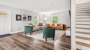 A modern living room with a wooden floor, two sofas, a coffee table, and artwork on the walls. - Bourbon Trail Near Buffalo Trace-Hot Tub, Fire Pit, BBQ Grill (Frankfort)