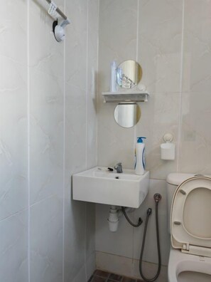 A small bathroom with a white sink, a mirror, and a toilet. - Langkawi Homestay Family Suite (Langkawi)