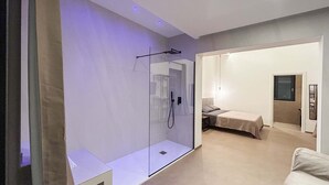 Une chambre moderne avec une douche en verre, un lit et une petite table.