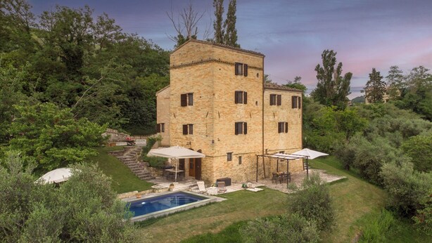 A stone building with a pool, outdoor seating, and a staircase leading to the entrance. - Casatorre 6+2, Emma Villas (Saludecio)