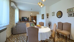 Un coin repas avec une table ronde, des chaises et un téléviseur en arrière-plan.