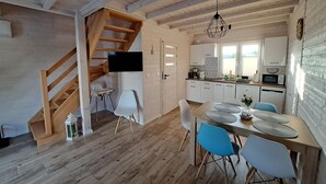 Eine moderne Küche mit Holzschränken, ein Essbereich mit Holztisch und Stühlen sowie eine Treppe zu einer weiteren Ebene.
