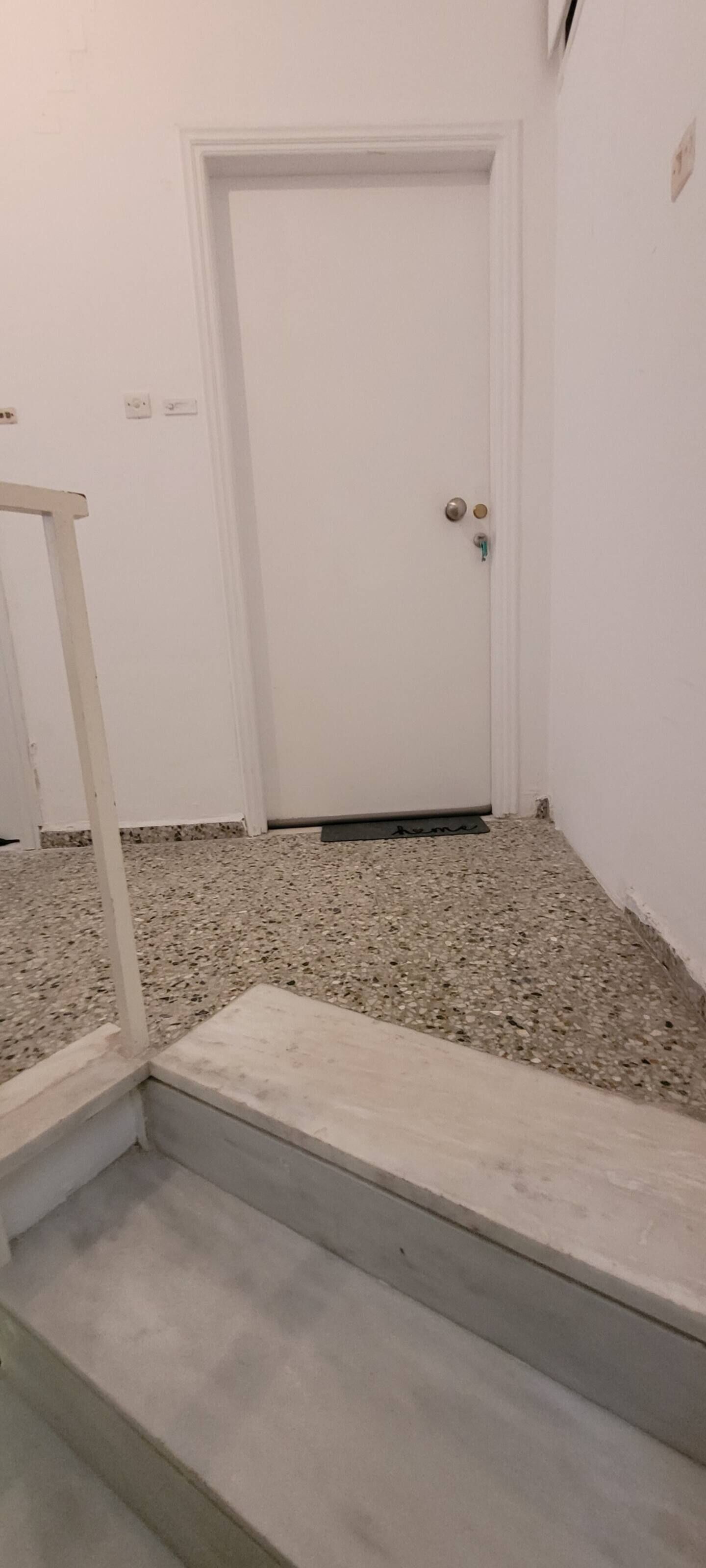 A staircase leading to a white door with a metal handle.