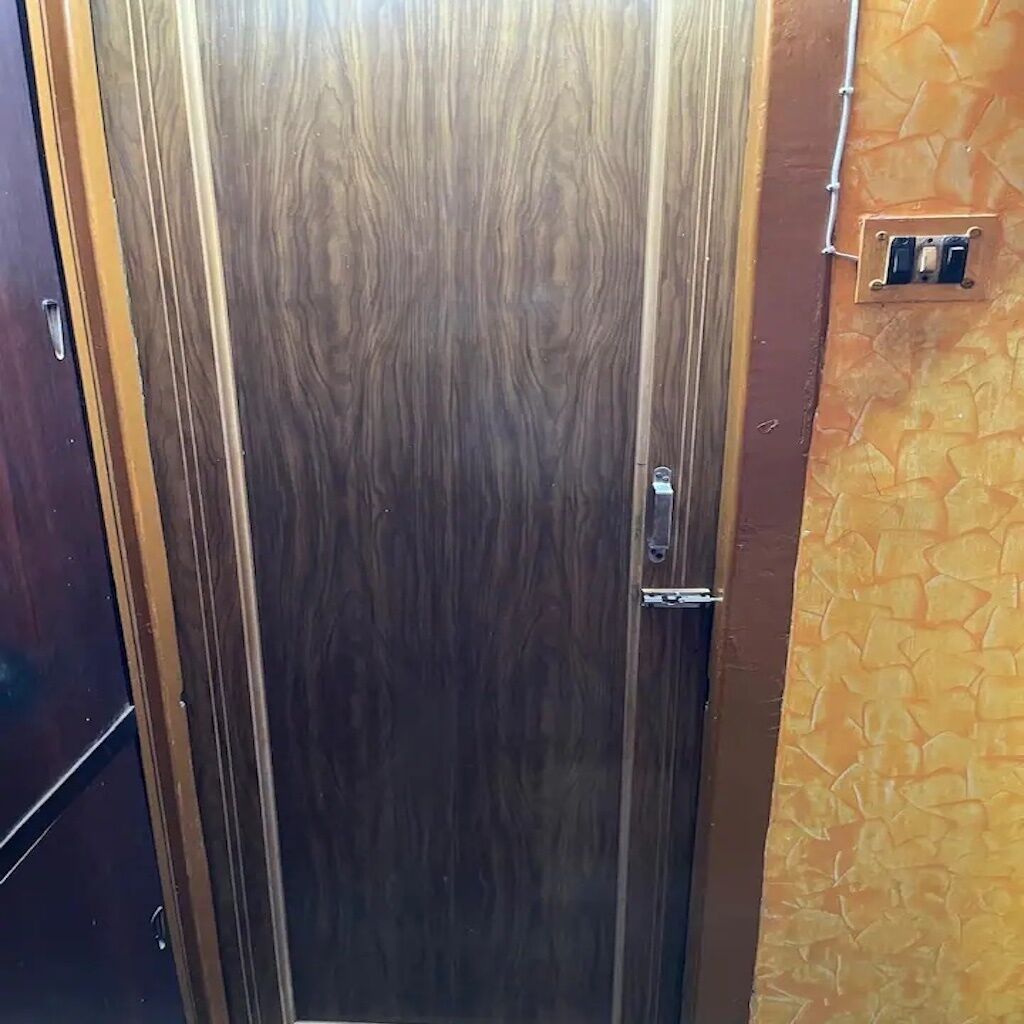 A wooden door with a handle and a light switch on the wall to the right.