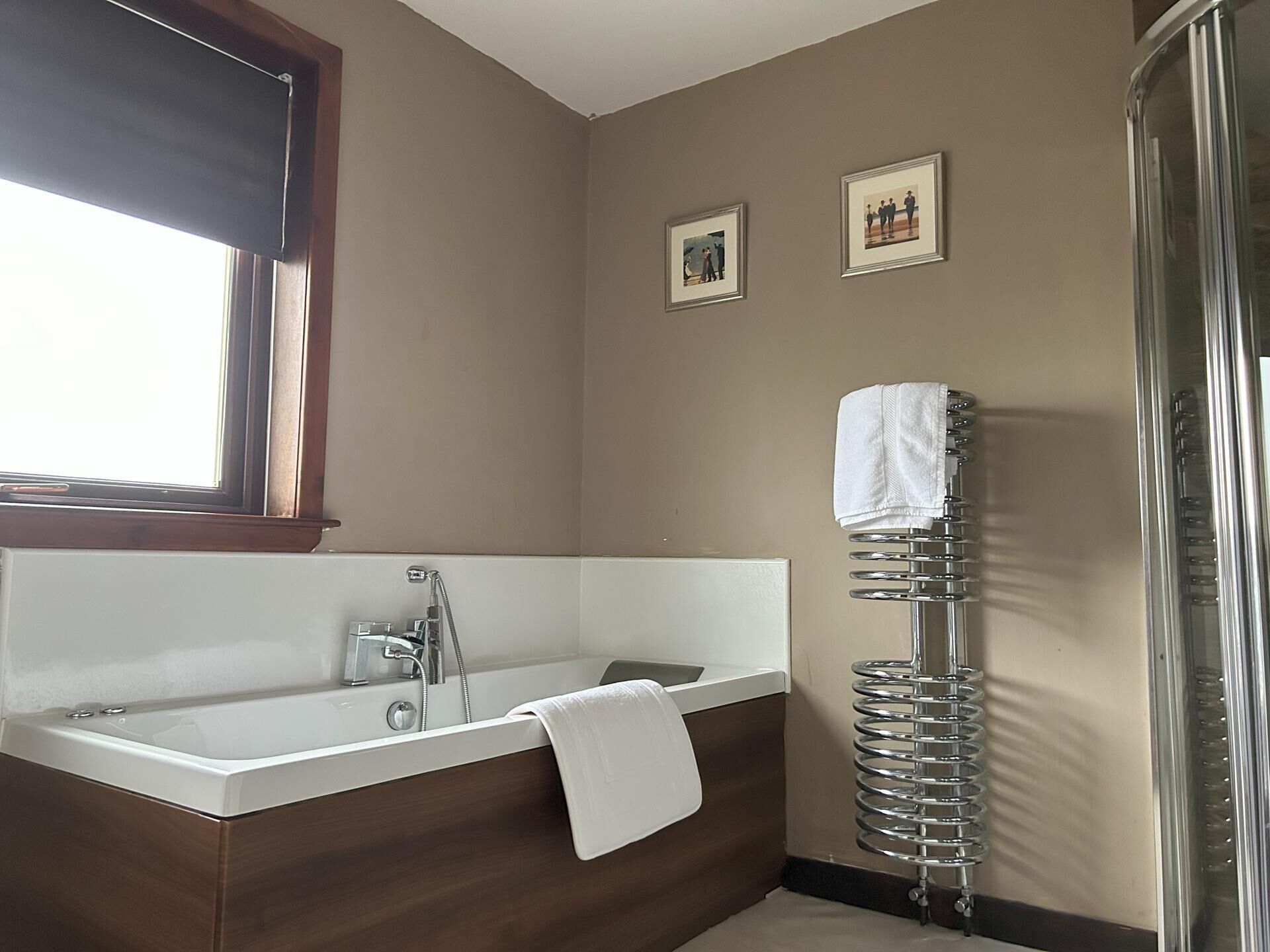 A bathroom with a bathtub, a shower, and a towel rack.