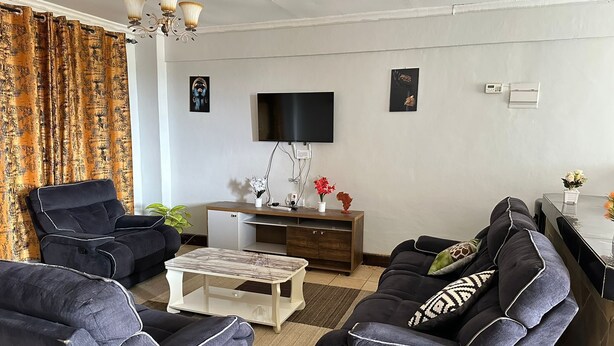 Una sala de estar con un sofá, una mesa de centro, un televisor y un mueble bajo.