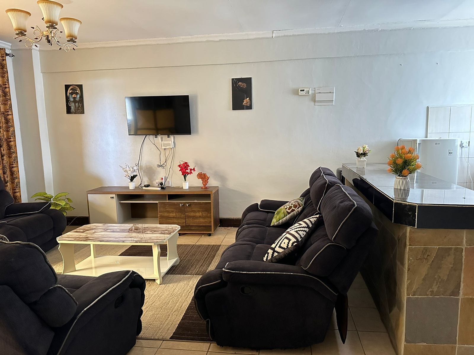 A living room with a sofa, a coffee table, a TV, and a small cabinet.