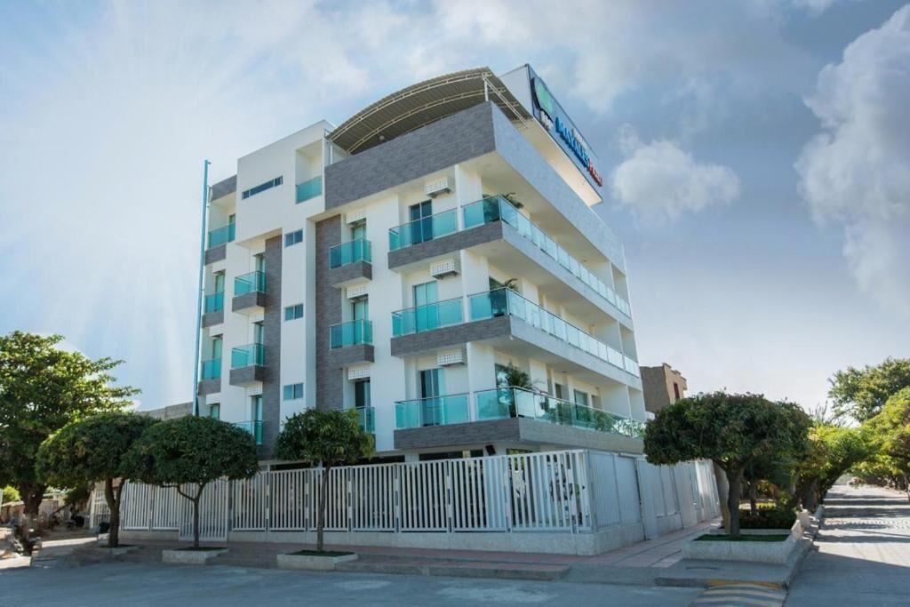 Un hotel de varios pisos con balcones, fachada blanca y cielo despejado.