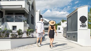 A couple walking on a paved pathway between modern buildings with a sign for 'Black Pearl'. - The Black Pearl Villas (Sithonia)