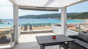 A balcony with a view of the beach, a table, and a sofa. - The Black Pearl Villas (Sithonia)