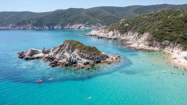 A coastal landscape with a rocky island surrounded by clear turquoise waters and a sandy beach. - The Black Pearl Villas (Sithonia)