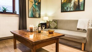A cozy living room with a wooden coffee table, a grey sofa, and abstract paintings on the walls.