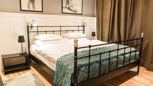A neatly made bed with a patterned bedspread, a bedside table with a lamp, and a wall-mounted artwork.