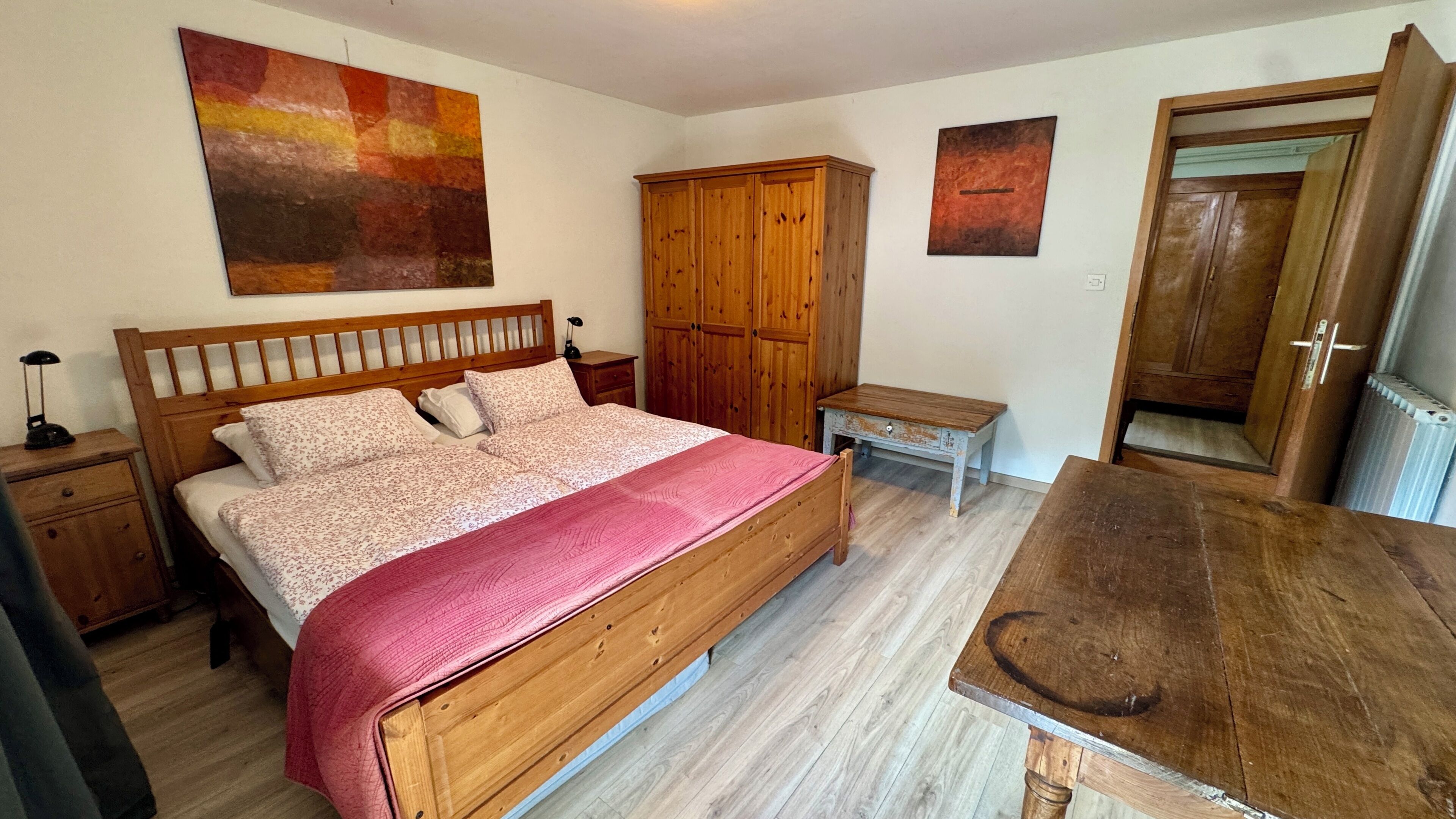 Une chambre à coucher avec un lit en bois, une table de chevet en bois, un banc en bois, une armoire en bois et une table en bois.