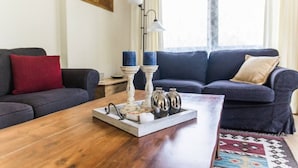 A living room with a wooden coffee table, two dark sofas, a red pillow, and a patterned rug. - Modern and renovated house in the beautiful Soca Valley (Kobarid)