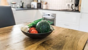 A kitchen with a wooden table holding a bowl of fresh vegetables. - Modern and renovated house in the beautiful Soca Valley (Kobarid)