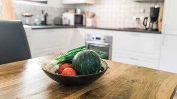 Une cuisine avec une table en bois sur laquelle se trouve un saladier rempli de légumes frais.