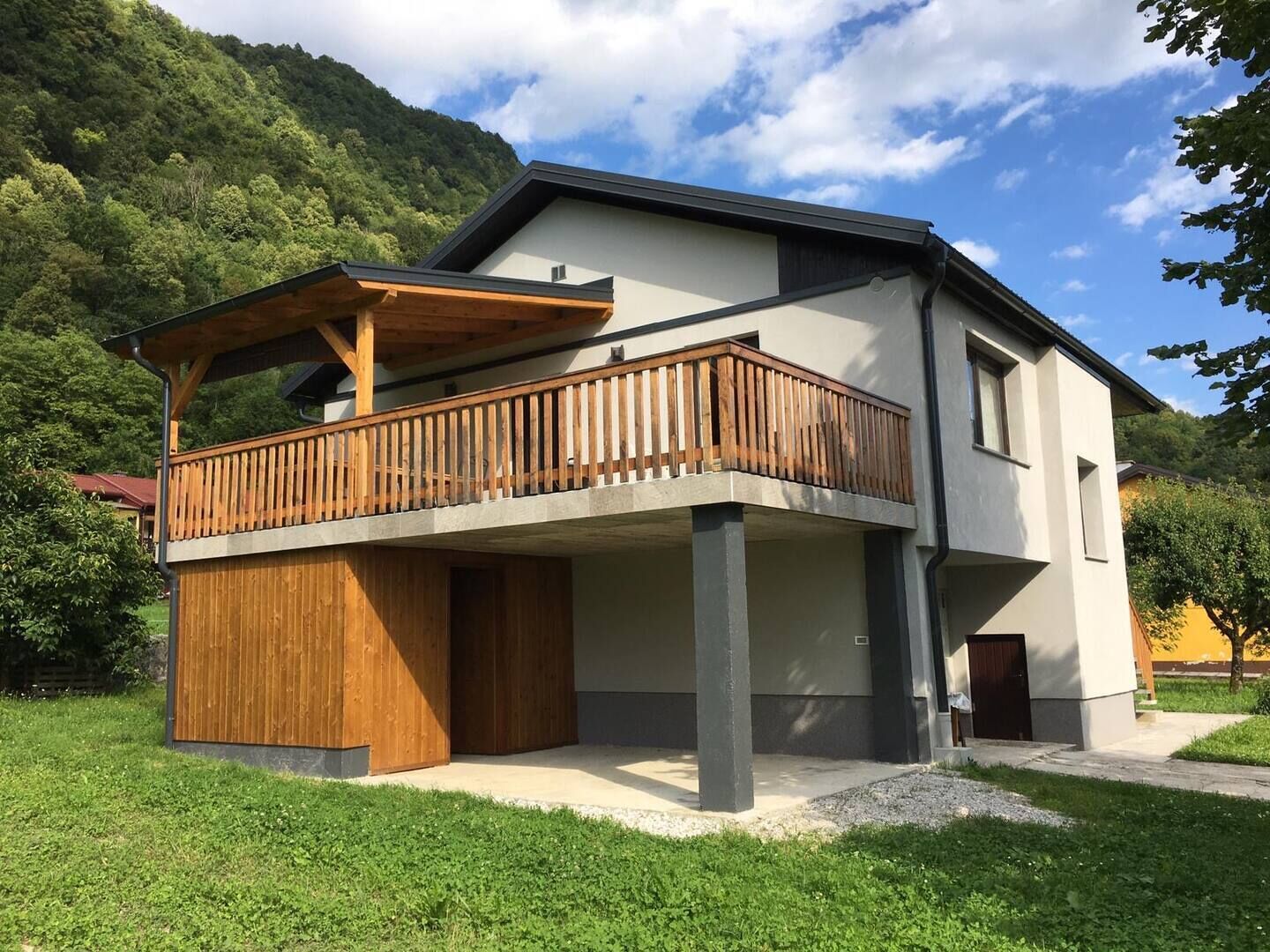 Une maison moderne à deux étages, dotée d’un balcon en bois et de fondations en béton.