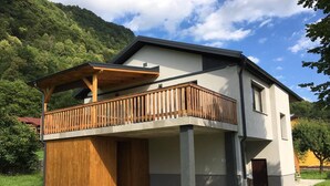 A modern two-story house with a wooden balcony and a concrete foundation. - Modern and renovated house in the beautiful Soca Valley (Kobarid)