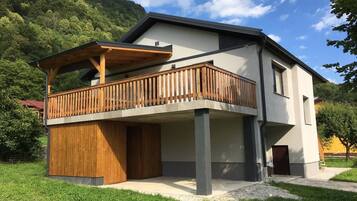 Une maison moderne à deux étages, dotée d’un balcon en bois et de fondations en béton.