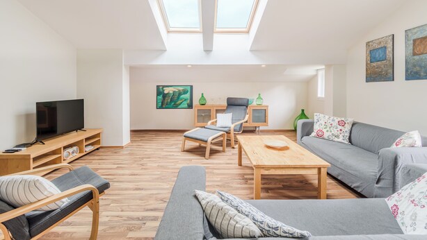 A spacious living area with a television, seating, artwork, and skylights. - Stylish apartment 100 m2 in Vila with lake view , sleeps 6, 2 bedrooms, airco, balcony (Most na Soči)