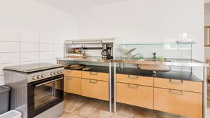 A modern kitchen with a built-in oven, a glass-fronted sink, and wooden cabinets. - Stylish apartment 100 m2 in Vila with lake view , sleeps 6, 2 bedrooms, airco, balcony (Most na Soči)