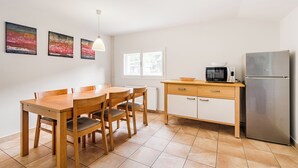 A modern kitchen with a wooden dining table, chairs, a refrigerator, a microwave, and a window. - Stylish apartment 100 m2 in Vila with lake view , sleeps 6, 2 bedrooms, airco, balcony (Most na Soči)