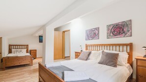 A bedroom with a wooden bed, a nightstand, a dresser, and two paintings on the wall. - Stylish apartment 100 m2 in Vila with lake view , sleeps 6, 2 bedrooms, airco, balcony (Most na Soči)