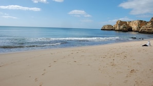 Une plage avec un ciel dégagé, une eau calme et des falaises rocheuses.