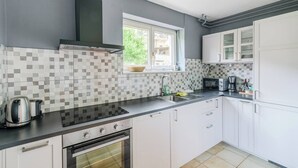 A modern kitchen with white cabinets, a black countertop, a built-in oven, a microwave, and a window with a view of greenery outside.