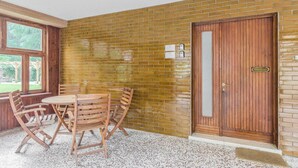A room with a brick wall, a wooden door, and a round table with chairs.