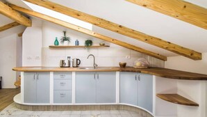 A kitchen with a curved countertop, wooden beams, and a tiled floor.