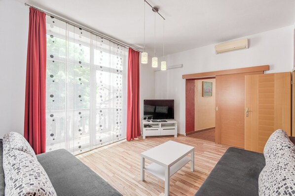 A modern living room with a TV, sofa, and a small white table.
