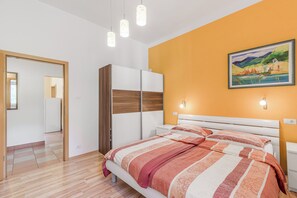 A bedroom with a bed, wardrobe, and a painting on the wall.