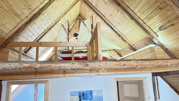 Un ático de madera con vigas a la vista y techo inclinado.