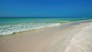 Une plage avec une eau d’un bleu limpide et un rivage sablonneux.