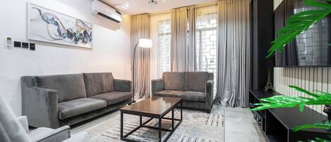 A modern living room with two sofas, a coffee table, and a TV stand.
