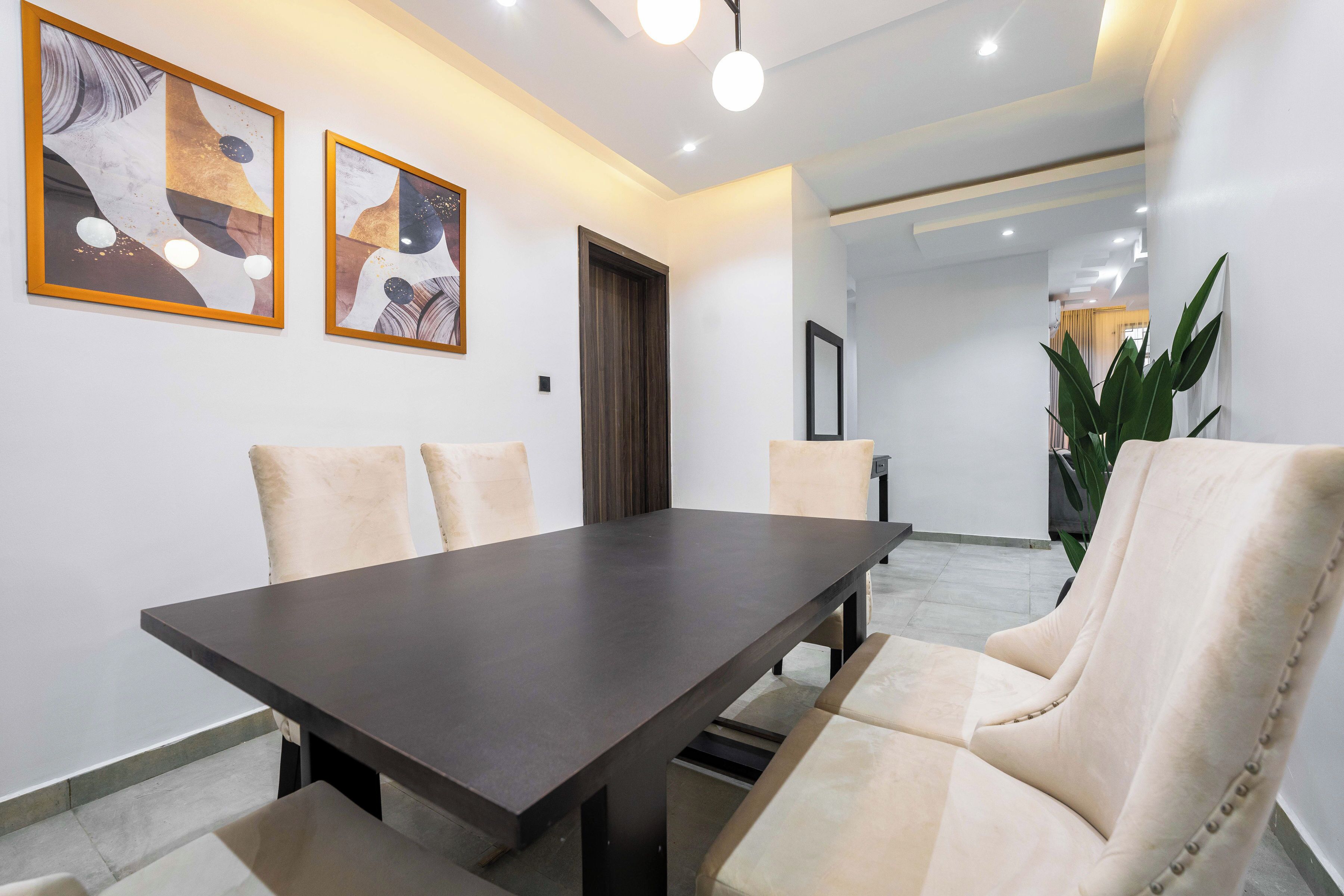 A modern dining area with a dark wooden table and cream-colored chairs.